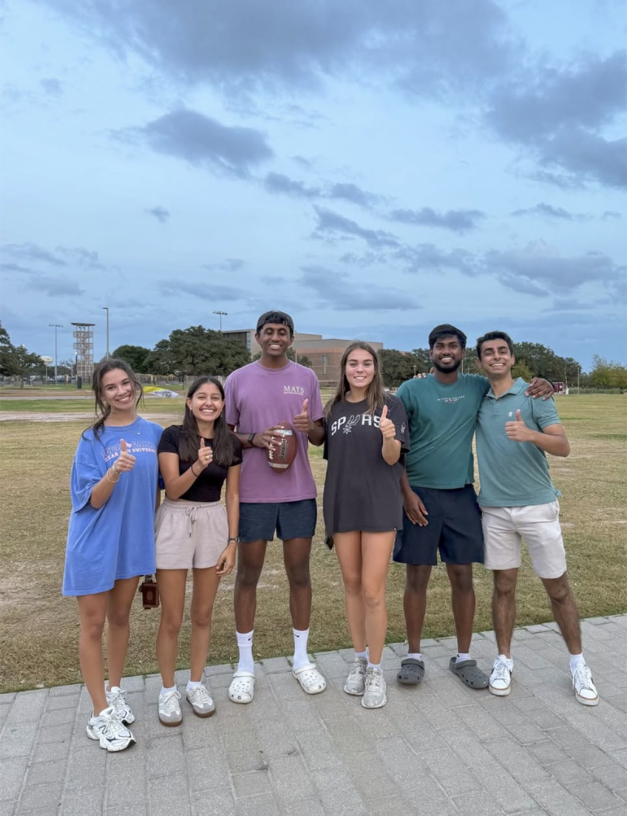 Members tossing a football on a campus field